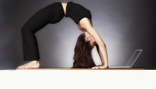 Woman in yoga pose looking at laptop